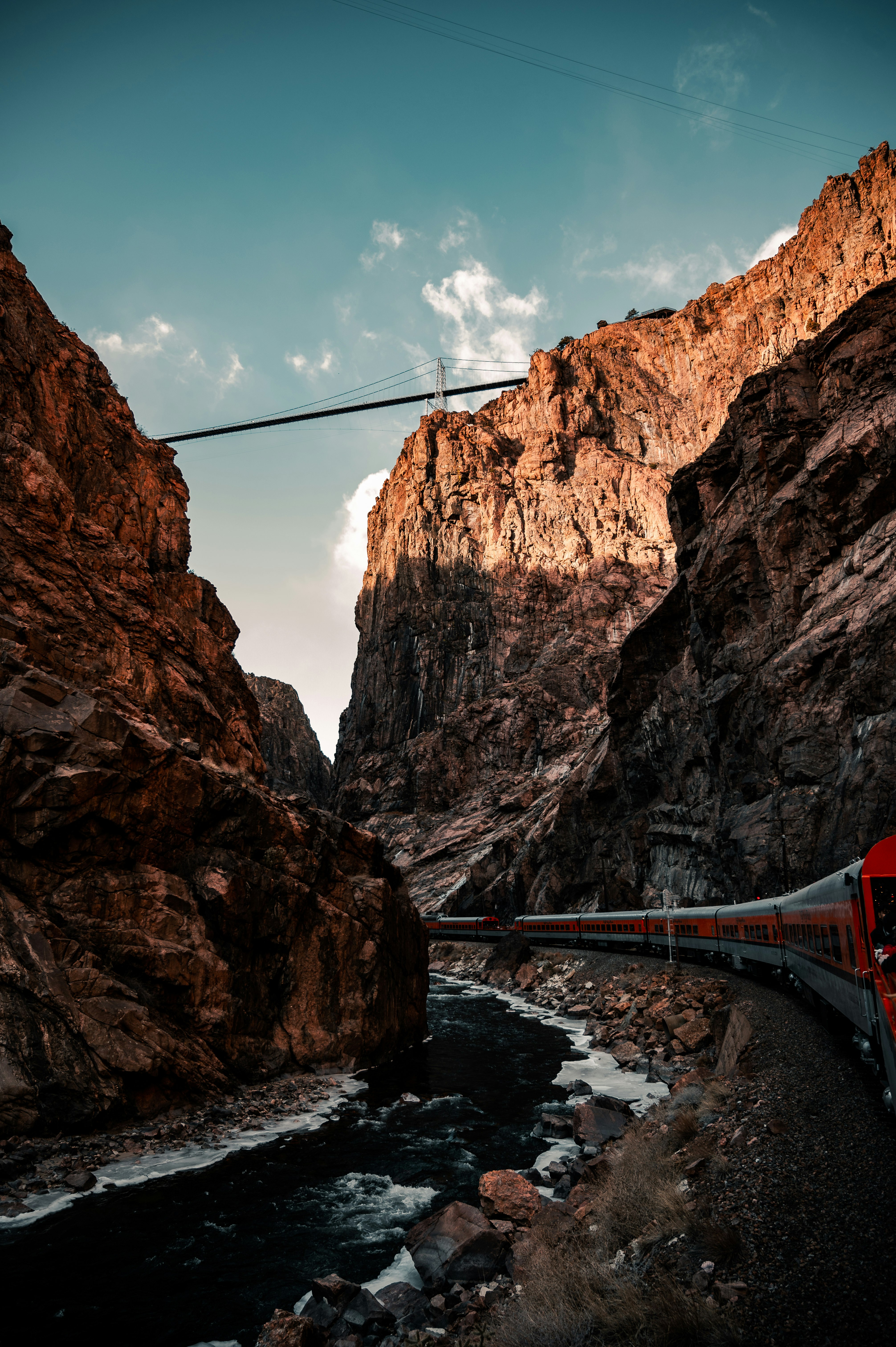 red bridge between brown rocky mountain during daytime